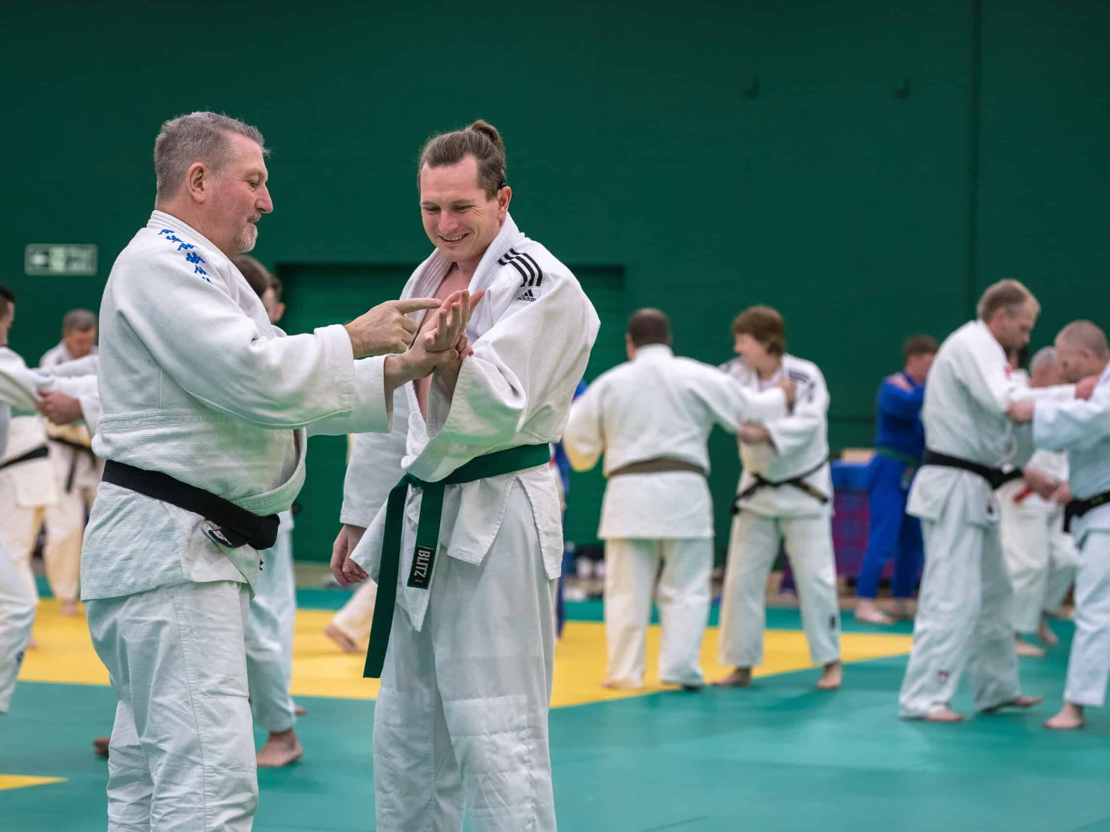 Judoka Chris Nicol with club coach Charlie Strachan communicating through tactile sign language on a judo mat.